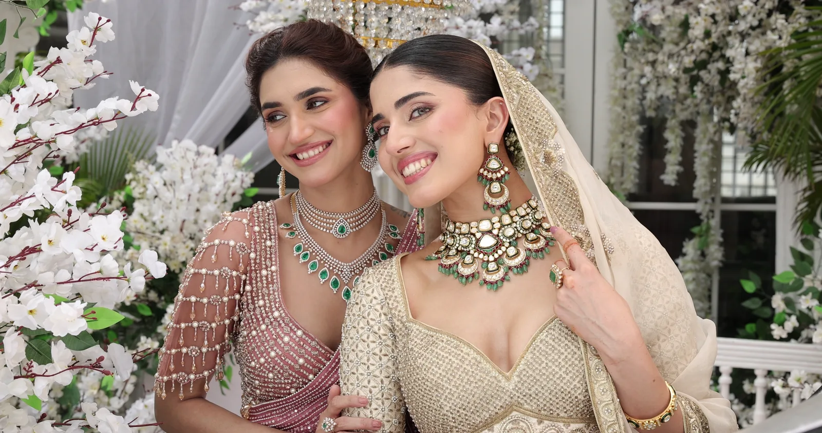 Two friends together in polki chokers beneath the blossom, laughing